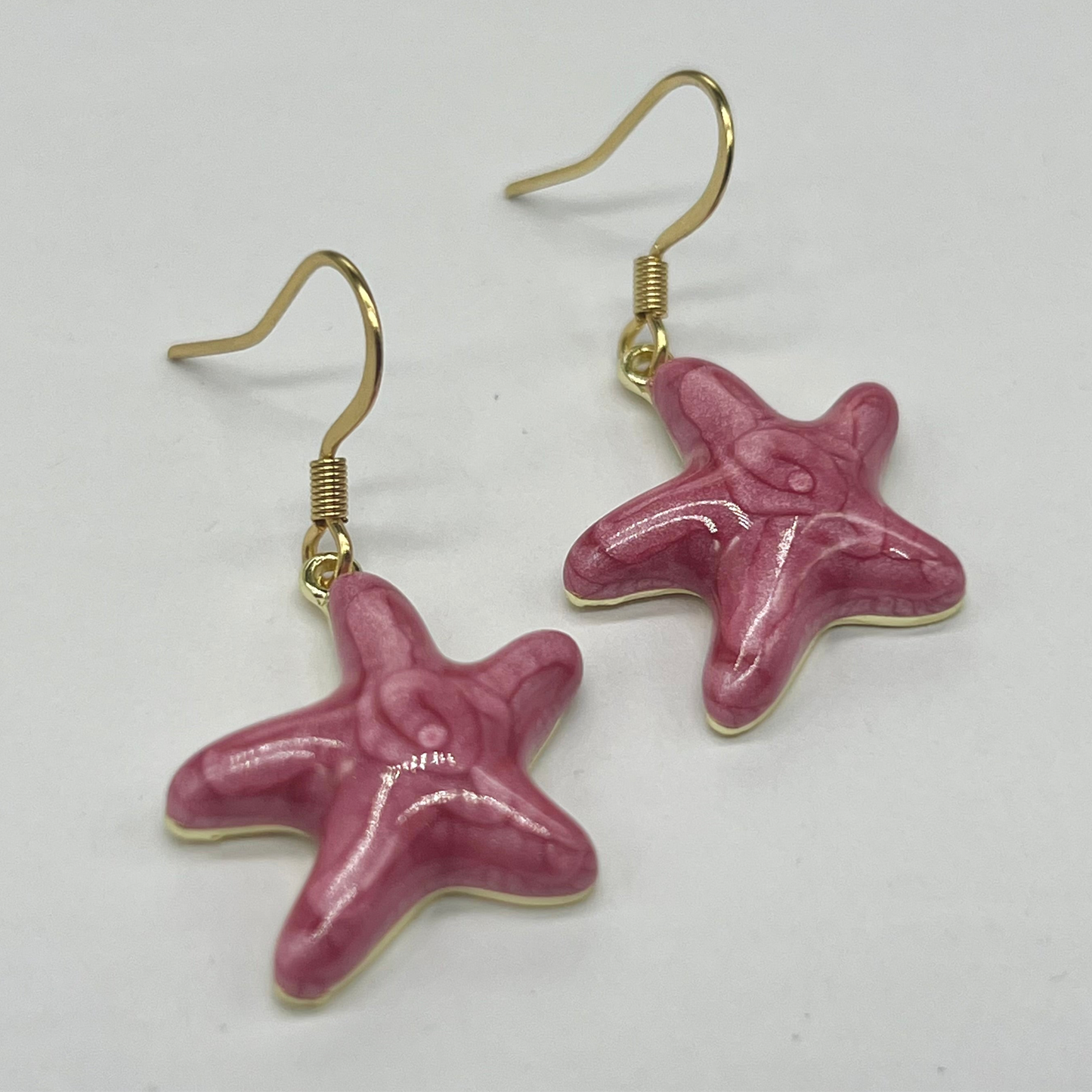 Pink starfish earrings on a white background