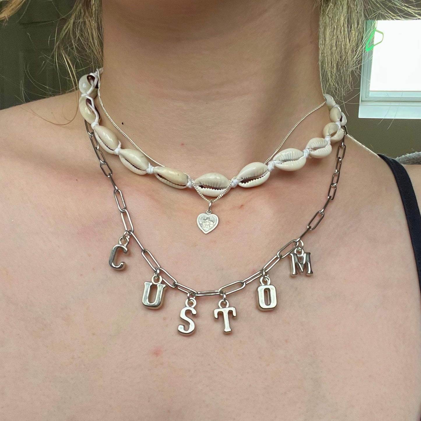 Necklace with letter charms worn by a person